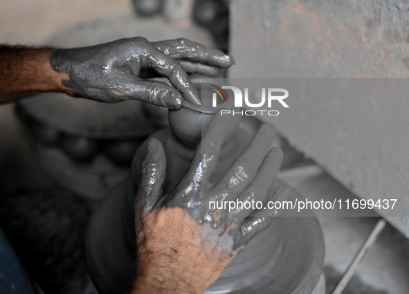 An Indian potter prepares an earthen pot to perform Laxmi Pooja at Kumbharwada potter's colony of Dharavi slum in preparation for Diwali, th...