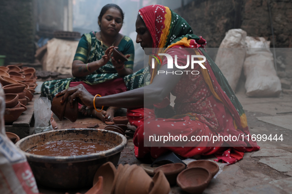 A woman prepares earthen diyas at Kumbharwada potter's colony of Dharavi slum in preparation for Diwali, the Hindu festival of lights, in Mu...