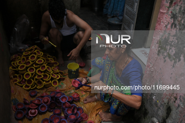 People color diyas (earthen lamps) at Kumbharwada potter's colony of Dharavi slum in preparation for Diwali (Hindu festival of lights), in M...