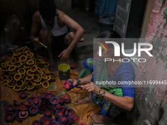 People color diyas (earthen lamps) at Kumbharwada potter's colony of Dharavi slum in preparation for Diwali (Hindu festival of lights), in M...