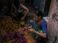 People color diyas (earthen lamps) at Kumbharwada potter's colony of Dharavi slum in preparation for Diwali (Hindu festival of lights), in M...