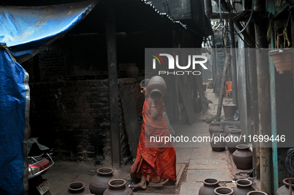 A woman carries an earthen pot at Kumbharwada potter's colony of Dharavi slum in preparation for Diwali (Hindu festival of lights), in Mumba...