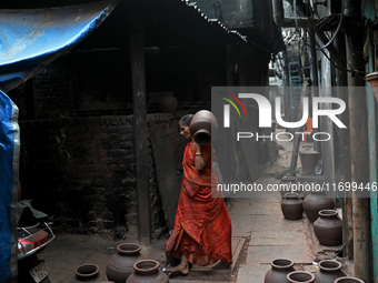 A woman carries an earthen pot at Kumbharwada potter's colony of Dharavi slum in preparation for Diwali (Hindu festival of lights), in Mumba...