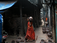 A woman carries an earthen pot at Kumbharwada potter's colony of Dharavi slum in preparation for Diwali (Hindu festival of lights), in Mumba...