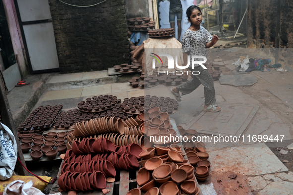 A child walks past diyas (earthen lamps) at Kumbharwada potter's colony of Dharavi slum in preparation for Diwali (Hindu festival of lights)...