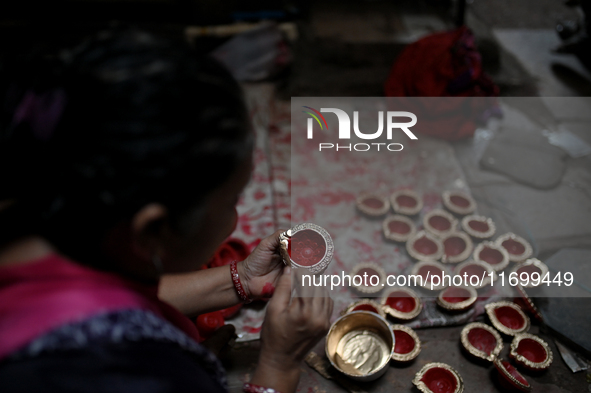 A woman colors diyas (earthen lamps) at Kumbharwada potter's colony of Dharavi slum in preparation for Diwali (Hindu festival of lights) in...