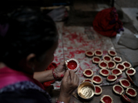 A woman colors diyas (earthen lamps) at Kumbharwada potter's colony of Dharavi slum in preparation for Diwali (Hindu festival of lights) in...