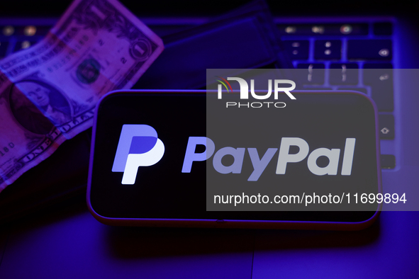 A laptop keyboard, a banknote, a wallet and PayPal logo displayed on a phone screen are seen in this illustration photo taken in Krakow, Pol...