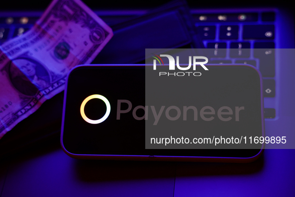 A laptop keyboard, a banknote, a wallet and Payoneer logo displayed on a phone screen are seen in this illustration photo taken in Krakow, P...