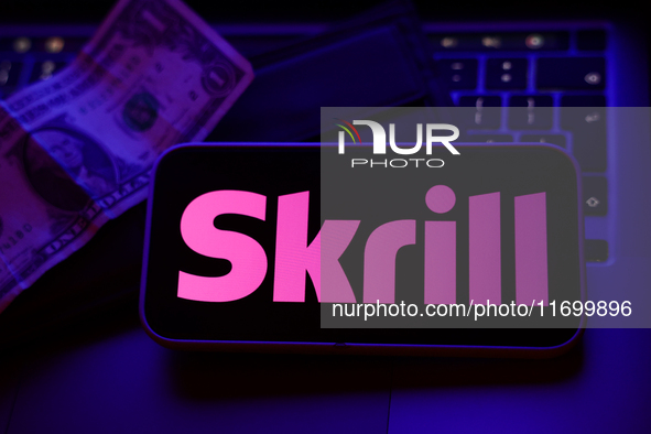 A laptop keyboard, a banknote, a wallet and Skrill logo displayed on a phone screen are seen in this illustration photo taken in Krakow, Pol...