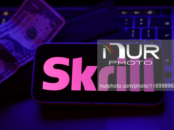 A laptop keyboard, a banknote, a wallet and Skrill logo displayed on a phone screen are seen in this illustration photo taken in Krakow, Pol...