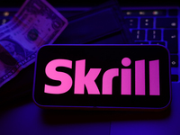 A laptop keyboard, a banknote, a wallet and Skrill logo displayed on a phone screen are seen in this illustration photo taken in Krakow, Pol...