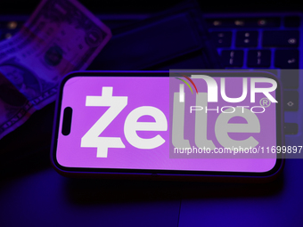 A laptop keyboard, a banknote, a wallet and Zelle logo displayed on a phone screen are seen in this illustration photo taken in Krakow, Pola...