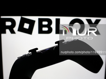 Roblox logo displayed on a laptop screen and DualSense controller are seen in this illustration photo taken in Krakow, Poland on October 23,...