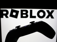 Roblox logo displayed on a laptop screen and DualSense controller are seen in this illustration photo taken in Krakow, Poland on October 23,...