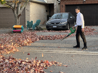 A boy uses a leaf blower to clear fallen leaves during the autumn season in Toronto, Ontario, Canada, on October 22, 2024. (