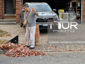 A man rakes leaves during the autumn season in Toronto, Ontario, Canada, on October 22, 2024. (