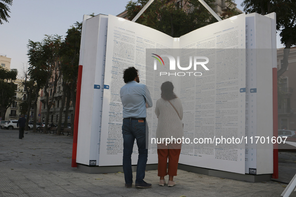 Two people observe a public art installation representing a monumental-sized dictionary in an urban space in Bari, Italy, on October 20, 201...