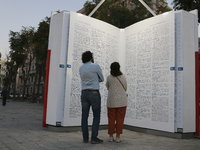 Two people observe a public art installation representing a monumental-sized dictionary in an urban space in Bari, Italy, on October 20, 201...