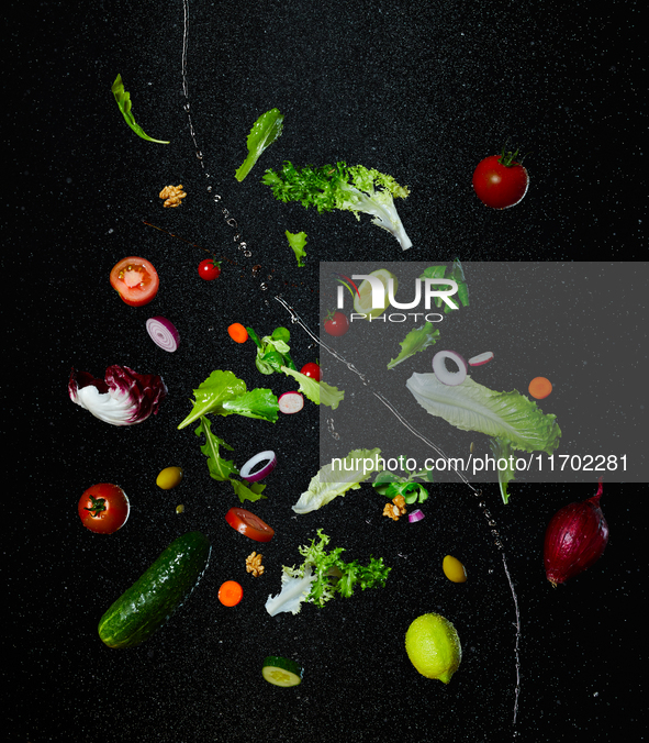 Creative food photography: Fresh salad ingredients suspend in mid-air against a dark background. The composition features lettuce leaves, ch...