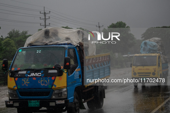 People cover themselves with polythene as they ride on a truck during rain in Dhaka, Bangladesh, on October 24, 2024. Light rain and wind fr...