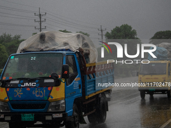 People cover themselves with polythene as they ride on a truck during rain in Dhaka, Bangladesh, on October 24, 2024. Light rain and wind fr...