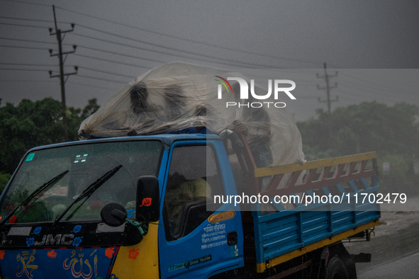 People cover themselves with polythene as they ride on a truck during rain in Dhaka, Bangladesh, on October 24, 2024. Light rain and wind fr...