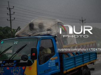 People cover themselves with polythene as they ride on a truck during rain in Dhaka, Bangladesh, on October 24, 2024. Light rain and wind fr...