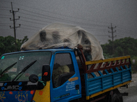 People cover themselves with polythene as they ride on a truck during rain in Dhaka, Bangladesh, on October 24, 2024. Light rain and wind fr...