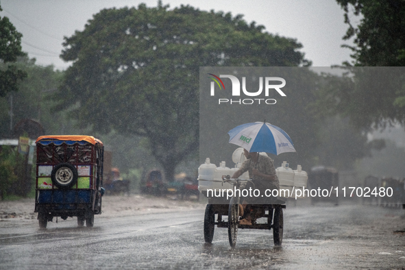 A worker carries jars of drinking water during rain in Dhaka, Bangladesh, on October 24, 2024. Light rain and wind from Cyclone Dana affect...