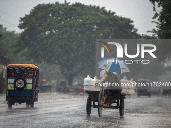 A worker carries jars of drinking water during rain in Dhaka, Bangladesh, on October 24, 2024. Light rain and wind from Cyclone Dana affect...