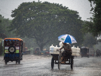 A worker carries jars of drinking water during rain in Dhaka, Bangladesh, on October 24, 2024. Light rain and wind from Cyclone Dana affect...