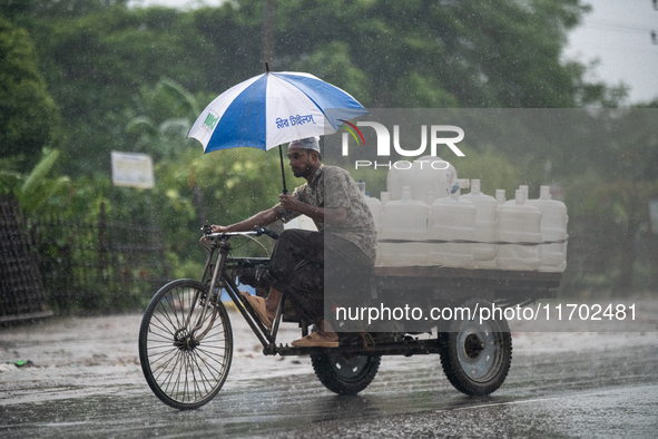 A worker carries jars of drinking water during rain in Dhaka, Bangladesh, on October 24, 2024. Light rain and wind from Cyclone Dana affect...