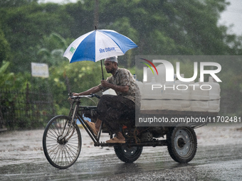 A worker carries jars of drinking water during rain in Dhaka, Bangladesh, on October 24, 2024. Light rain and wind from Cyclone Dana affect...