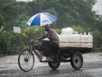 A worker carries jars of drinking water during rain in Dhaka, Bangladesh, on October 24, 2024. Light rain and wind from Cyclone Dana affect...