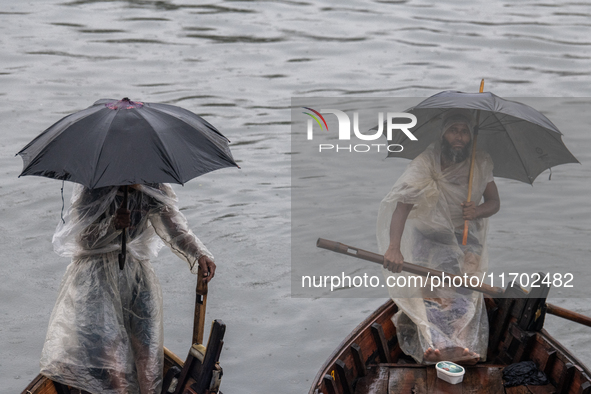 Boatmen wait for passengers at the river Buriganga during rain in Dhaka, Bangladesh, on October 24, 2024. Light rain and wind from Cyclone D...