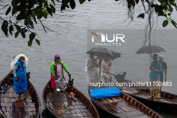 Boatmen wait for passengers at the river Buriganga during rain in Dhaka, Bangladesh, on October 24, 2024. Light rain and wind from Cyclone D...