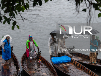 Boatmen wait for passengers at the river Buriganga during rain in Dhaka, Bangladesh, on October 24, 2024. Light rain and wind from Cyclone D...