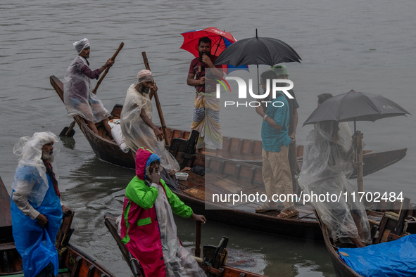 Passengers hold umbrellas as they cross the Buriganga River during rain in Dhaka, Bangladesh, on October 24, 2024. Light rain and wind from...