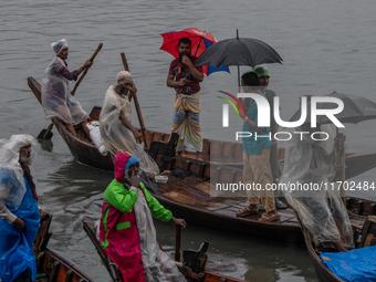 Passengers hold umbrellas as they cross the Buriganga River during rain in Dhaka, Bangladesh, on October 24, 2024. Light rain and wind from...