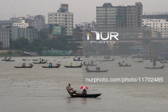 Passengers hold umbrellas as they cross the Buriganga River during rain in Dhaka, Bangladesh, on October 24, 2024. Light rain and wind from...