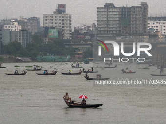 Passengers hold umbrellas as they cross the Buriganga River during rain in Dhaka, Bangladesh, on October 24, 2024. Light rain and wind from...