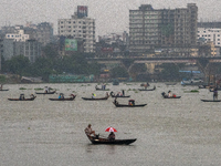 Passengers hold umbrellas as they cross the Buriganga River during rain in Dhaka, Bangladesh, on October 24, 2024. Light rain and wind from...