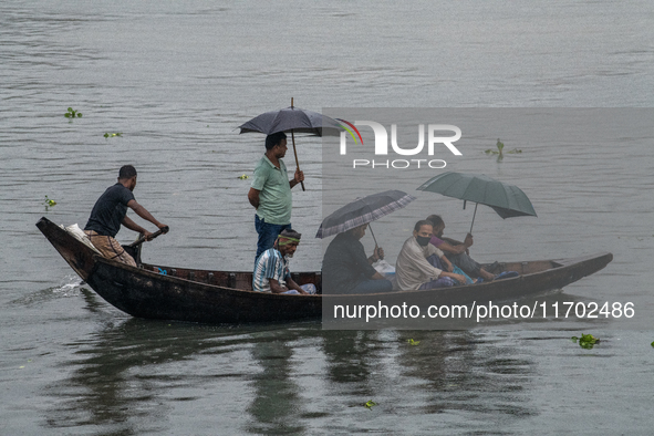 Passengers hold umbrellas as they cross the Buriganga River during rain in Dhaka, Bangladesh, on October 24, 2024. Light rain and wind from...