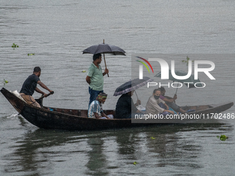 Passengers hold umbrellas as they cross the Buriganga River during rain in Dhaka, Bangladesh, on October 24, 2024. Light rain and wind from...