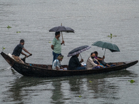 Passengers hold umbrellas as they cross the Buriganga River during rain in Dhaka, Bangladesh, on October 24, 2024. Light rain and wind from...