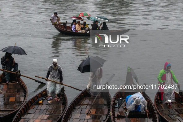 Passengers hold umbrellas as they cross the Buriganga River during rain in Dhaka, Bangladesh, on October 24, 2024. Light rain and wind from...