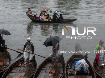 Passengers hold umbrellas as they cross the Buriganga River during rain in Dhaka, Bangladesh, on October 24, 2024. Light rain and wind from...