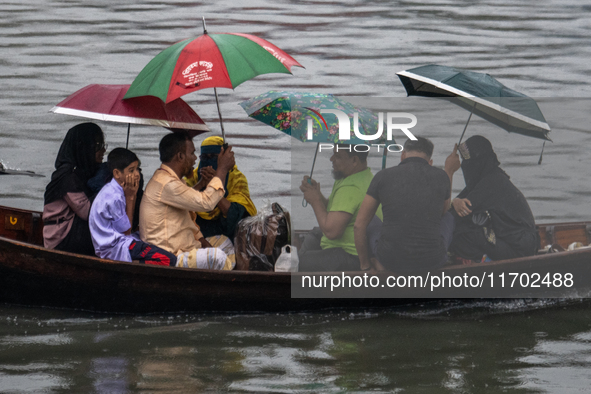 Passengers hold umbrellas as they cross the Buriganga River during rain in Dhaka, Bangladesh, on October 24, 2024. Light rain and wind from...