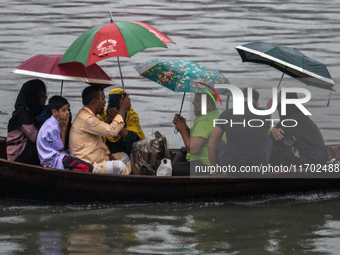 Passengers hold umbrellas as they cross the Buriganga River during rain in Dhaka, Bangladesh, on October 24, 2024. Light rain and wind from...